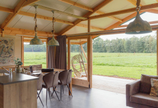 Interieur van een glamping-accommodatie bij Landrijk de Reesprong met uitzicht op groene weiden en natuur.