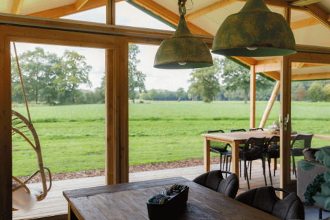Vista desde el glamping Landrijk de Reesprong con decoración rústica y panorámica de campos verdes.