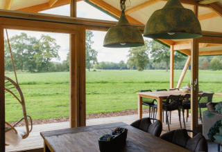 Vista desde el glamping Landrijk de Reesprong con decoración rústica y panorámica de campos verdes.