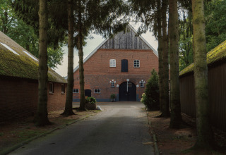 Indgang til Glamping - Landrijk de Reesprong med træer og traditionelle bygninger på begge sider.