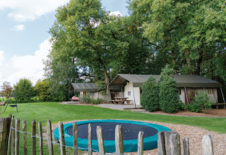 Alloggio glamping a Landrijk de Reesprong con tende, prato verde, trampolino e area picnic all'aperto.