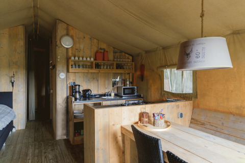 Alloggio glamping con cucina in legno e zona pranzo al Landrijk de Reesprong nei Paesi Bassi.
