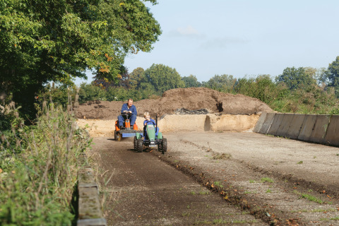 Father and child riding mini tractors at Glamping - Landrijk de Reesprong, surrounded by nature and trees.