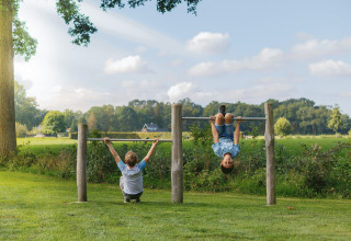 Kinder spielen an einer Kletterstange im Grünen bei Glamping - Landrijk de Reesprong auf dem Land.