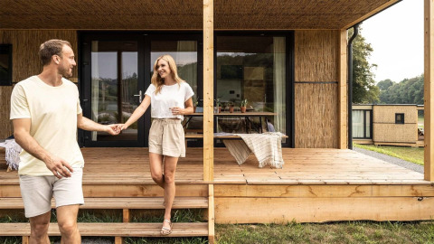 Et ungt par nyder deres ophold foran en hyggelig glamping-hytte på Falkensteiner Premium Camping Blaguš i Slovenien.