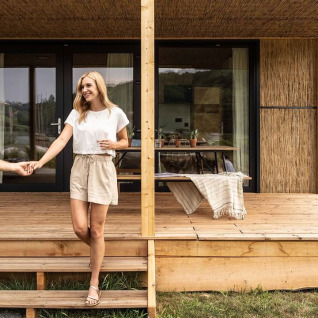 Et ungt par nyder deres ophold foran en hyggelig glamping-hytte på Falkensteiner Premium Camping Blaguš i Slovenien.