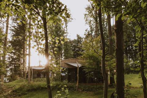 Alloggio glamping di lusso tra gli alberi al Falkensteiner Premium Camping Blaguš in Slovenia al tramonto.