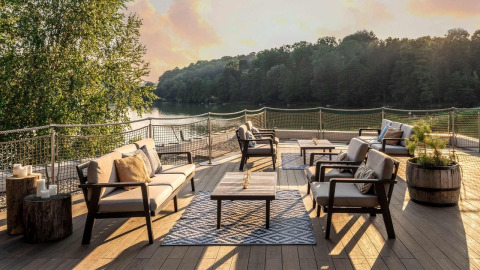 Buitenterras met zithoek aan het meer bij Falkensteiner Premium Camping Blaguš Glamping Slovenië bij zonsondergang.