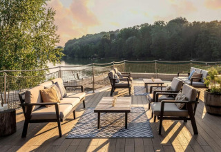 Udendørs loungeområde ved søen på Falkensteiner Premium Camping Blaguš Glamping Slovenien ved solnedgang.