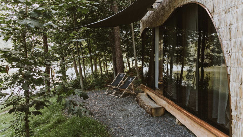 Area esterna al Falkensteiner Premium Camping Blaguš Glamping in Slovenia, con sedie e vista sul bosco.