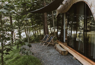 Zona exterior en Falkensteiner Premium Camping Blaguš Glamping Eslovenia, con sillas y vista al bosque.