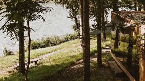 Scenic glamping by the lake at Falkensteiner Premium Camping Blaguš, Slovenia, with modern mirrored cabins in nature.