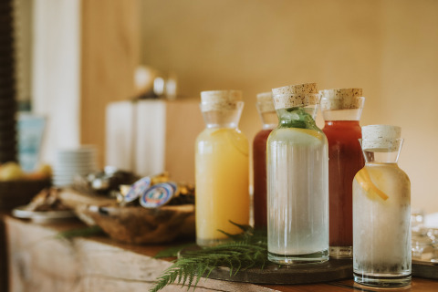 Bouteilles de jus diverses avec bouchons disposées sur table rustique au glamping Falkensteiner Blaguš.