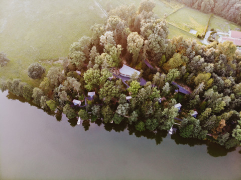 Vista aerea di Falkensteiner Premium Camping Blaguš glamping in Slovenia, vicino a un lago tra alberi.
