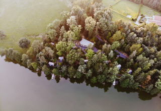 Vista aérea de Falkensteiner Premium Camping Blaguš glamping en Eslovenia, junto a un lago y bosques.