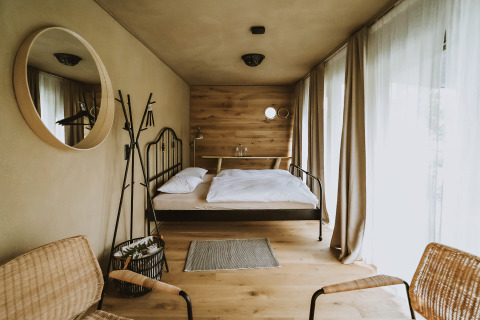 Stylish glamping accommodation with a floating bed, large windows, and minimalist decor at Falkensteiner Premium Camping Blaguš.