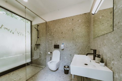 Moderne badeværelse med glasbruser, toilet, håndvask og minimalistisk design i Falkensteiner Premium Camping Blaguš, Slovenien.