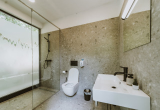 Modernes Badezimmer mit Glasdusche, Toilette und Waschbecken im Falkensteiner Premium Camping Blaguš, Slowenien.