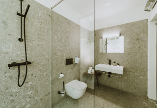 Moderne badkamer bij Falkensteiner Premium Camping Blaguš Glamping Slovenië met regendouche en wastafel.