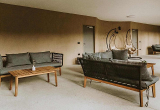 Espace lounge extérieur avec canapés modernes et fauteuils suspendus au Falkensteiner Premium Camping Blaguš Glamping Slovénie.