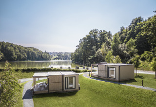 Hébergements glamping au Falkensteiner Premium Camping Blaguš au bord d’un lac entouré de verdure en Slovénie.