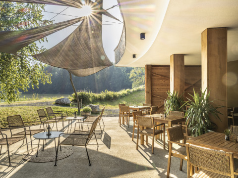 Terraza al aire libre con muebles modernos y toldos en Falkensteiner Premium Camping Blaguš, Eslovenia.