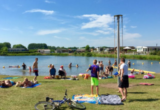 Familien und Gäste entspannen sich am Ufer der See im Glamping De Betuwse Hofjes - Ranger Lodges Gelderland.