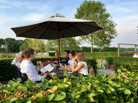 Comida al aire libre bajo sombrilla en De Betuwse Hofjes - Ranger Lodges Gelderland, rodeado de vegetación.