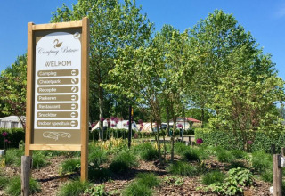 Welkomstbord bij Camping Betuwe met wegwijzers naar camping, chaletpark, receptie en restaurant.