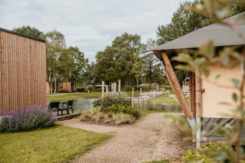 Alojamiento glamping en De Betuwse Hofjes - Ranger Lodges Gelderland con cabañas de madera y vista al estanque.