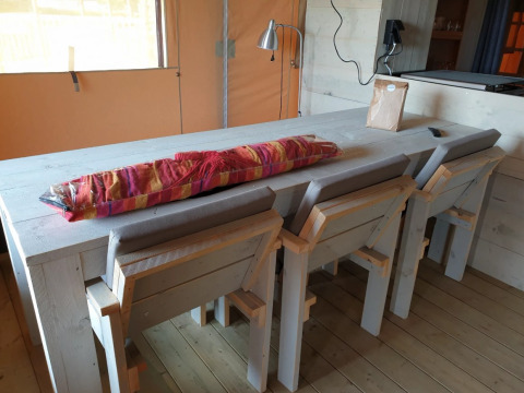 Essbereich mit Holztisch und Stühlen in einer Glamping-Unterkunft bei De Betuwse Hofjes - Ranger Lodges Gelderland.