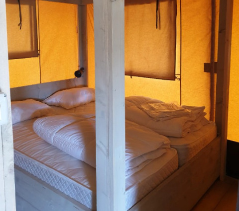 Innenaufnahme einer Glampingunterkunft mit gemütlichen Betten bei De Betuwse Hofjes - Ranger Lodges Gelderland.