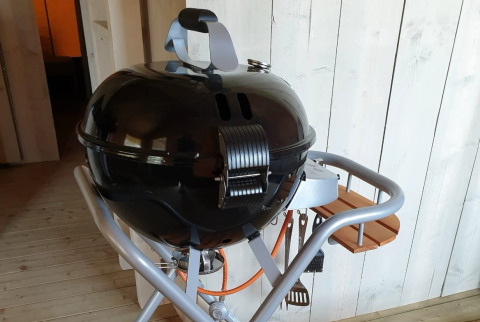 Schwarzer Kugelgrill mit Deckel und Werkzeugen im Glamping der De Betuwse Hofjes - Ranger Lodges Gelderland.