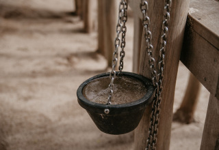 Cuenco negro colgante con cadenas en poste de madera en De Betuwse Hofjes - Ranger Lodges Gelderland camping.