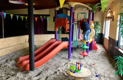 Parco giochi al coperto con sabbia, scivoli e strutture colorate presso De Betuwse Hofjes - Ranger Lodges.