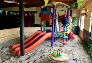 Aire de jeux intérieure avec sable, toboggans colorés et structures à grimper à De Betuwse Hofjes - Ranger Lodges.