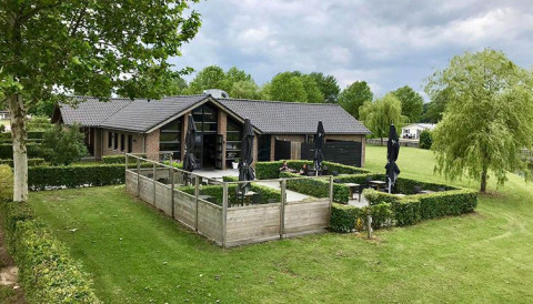 Alloggio glamping De Betuwse Hofjes - Ranger Lodges Gelderland con lodge moderno e giardino verde.