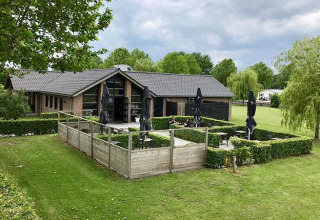 Glamping indkvartering De Betuwse Hofjes - Ranger Lodges i Gelderland, omgivet af grønt og have.