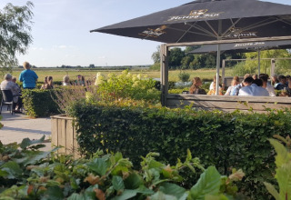 Zona de comedor al aire libre en De Betuwse Hofjes - Ranger Lodges Gelderland con vistas verdes y gente.