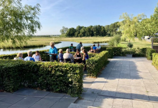 Espace de restauration extérieur aux De Betuwse Hofjes - Ranger Lodges Gelderland, près d'une rivière paisible.