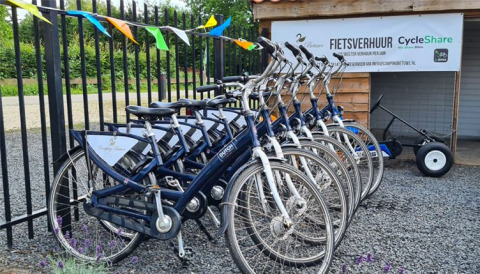Alquiler de bicicletas en De Betuwse Hofjes - Ranger Lodges Gelderland con varias bicis azules aparcadas.