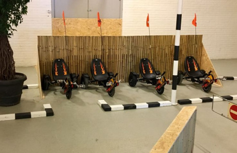 Vier zwarte skelters met vlammen en oranje vlaggen staan binnen geparkeerd bij een bamboewand bij De Betuwse Hofjes.