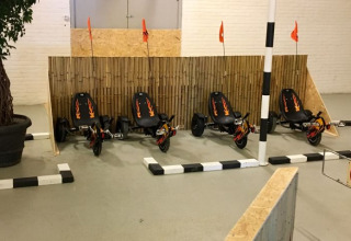 Fire sorte gokarts med flammer og orange flag parkeret ved en bambusvæg indendørs ved De Betuwse Hofjes.