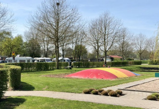 Campground with bouncy pillow and caravans at De Betuwse Hofjes - Ranger Lodges Gelderland on a sunny day.