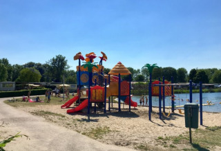 Legeplads og strand ved De Betuwse Hofjes - Ranger Lodges Gelderland camping under en klar blå himmel.