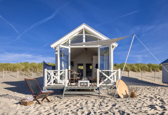 Maison de plage de luxe à La Haye avec terrasse, mobilier extérieur et auvent sur une plage de sable.