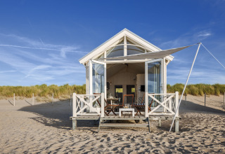 Un chalet de plage de luxe HaagseStrandhuisjes sur le sable à La Haye, sous un ciel bleu éclatant.