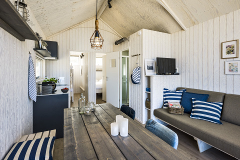 Moderne glamping strandhytte med maritime detaljer, spisestue, køkken og komfortabel sofa i Den Haag.
