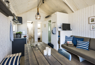 Cabane de glamping moderne au bord de la mer à La Haye, déco nautique, cuisine et canapé convivial.