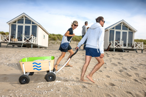 Gezin trekt een kar op het zand voor luxe strandhuisjes bij HaagseStrandhuisjes in Den Haag.